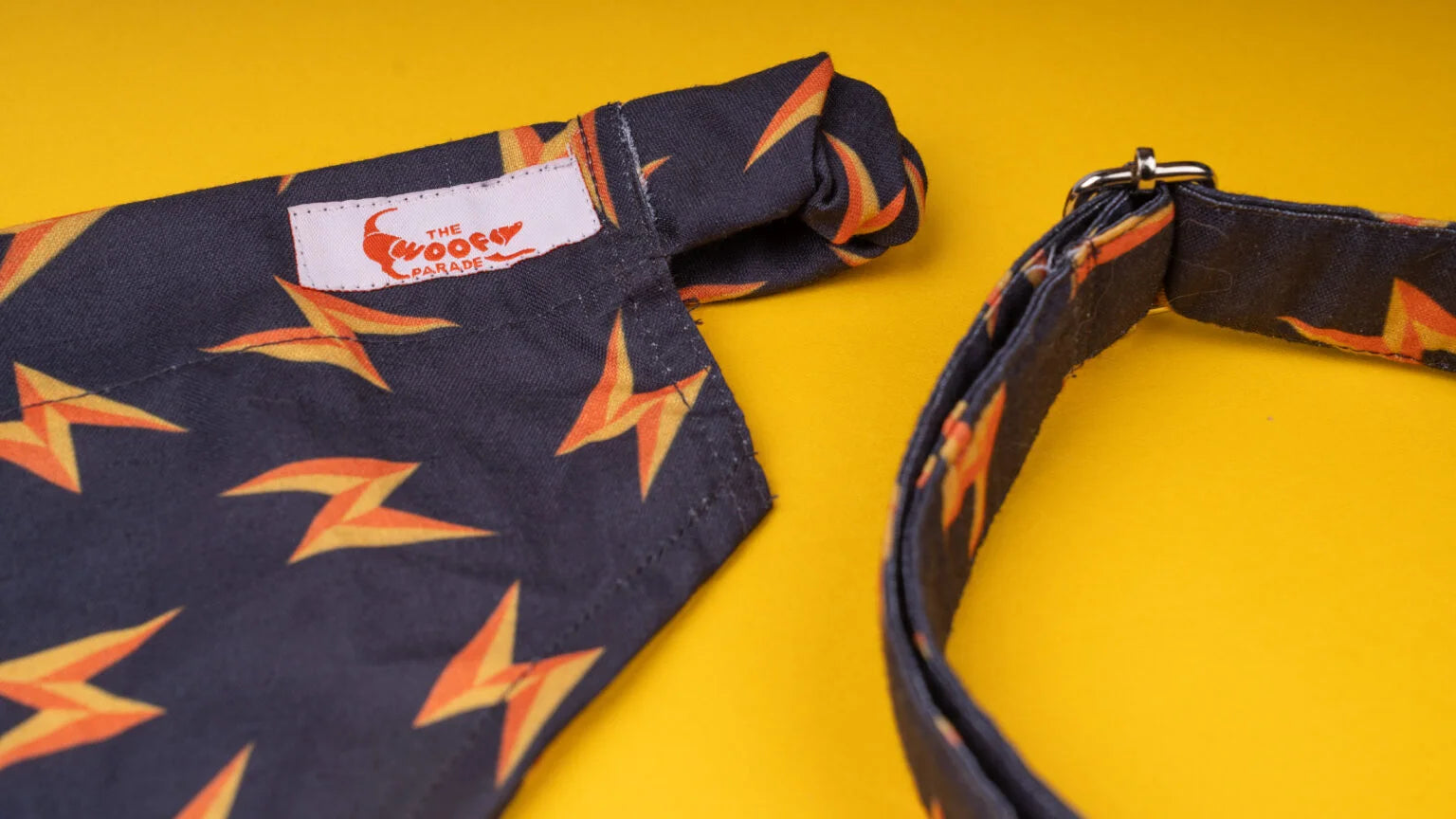 Close-up of the vibrant orange lightning bolt print on a matching dog bandana and collar set by The Woof Parade.